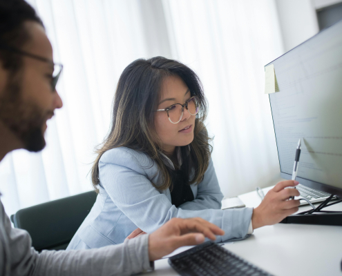 woman and man looking at computer screen talking