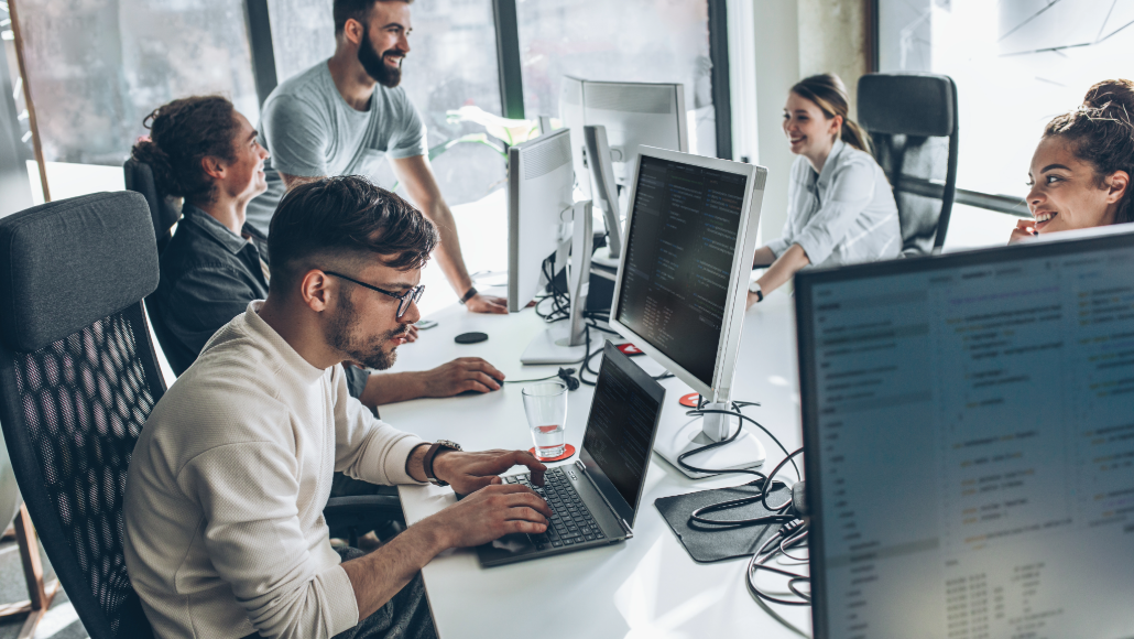 software developer team working on computers while smiling